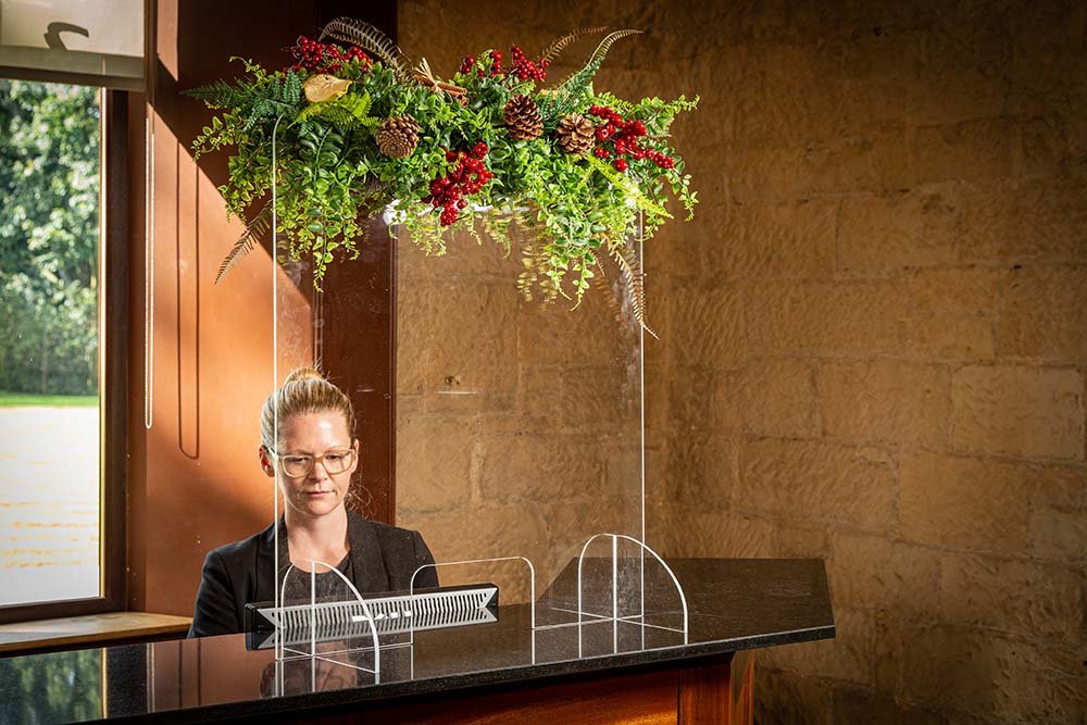 Hotel reception screen decorated with seasonal floral screen topper inc greenery, red berries and natural pine cones