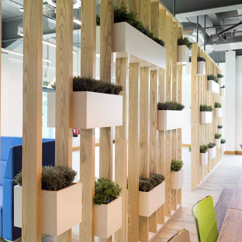 White rectangular and cube planters inset into wooden slats to create a soft divider in an open plan office space