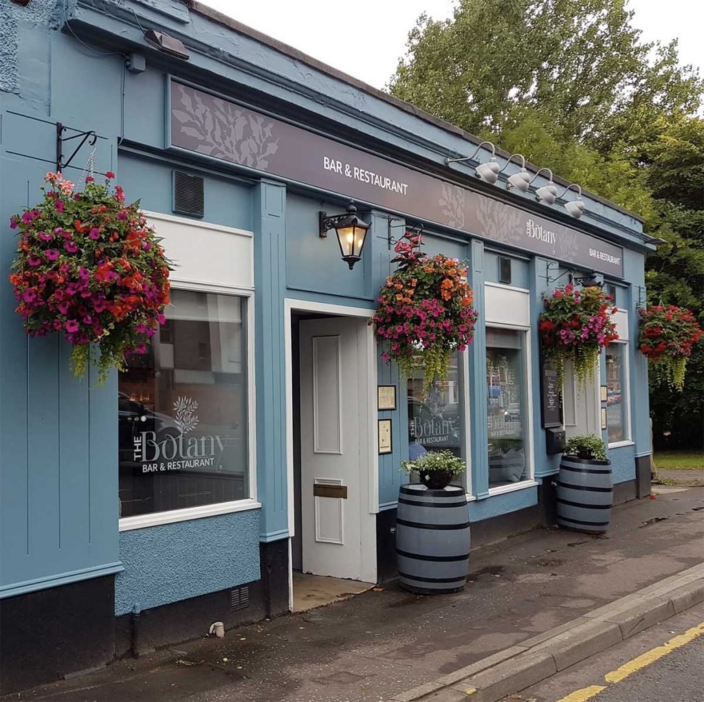 Beautiful hanging baskets in full bloom with orange and purple flowers and trailing foliage for a restaurant