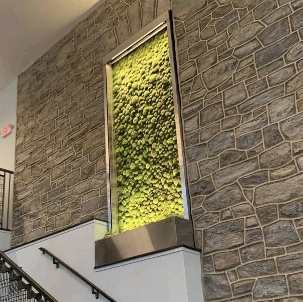 Illuminated bun moss wall panel in a silver frame against a stone effect wall to create an feature on a stairwell