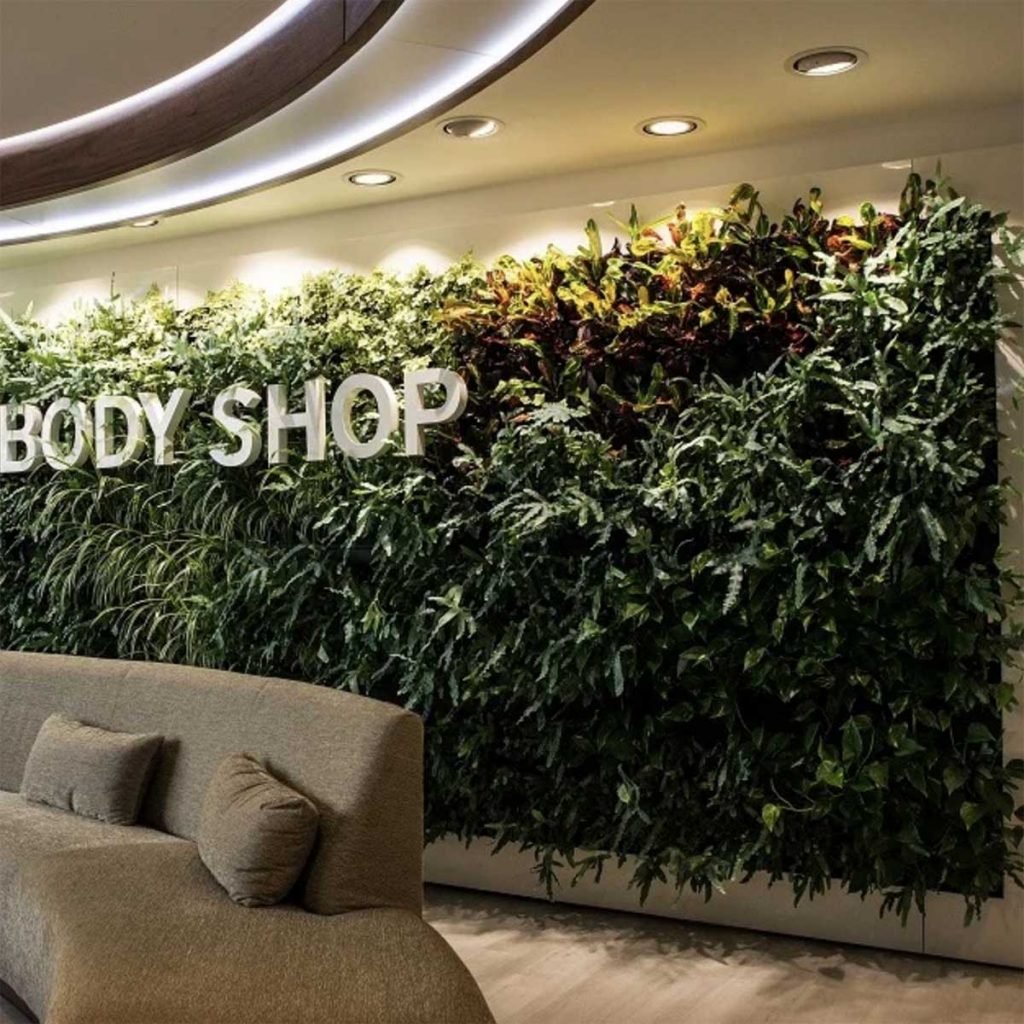 Living wall bursting with plants, full of tones and textures on a curved wall with Bodyshop logo sat atop